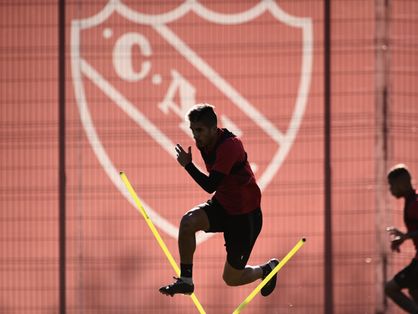 Atleta salta no treino do Independiente-ARG, na frente do escudo do clube