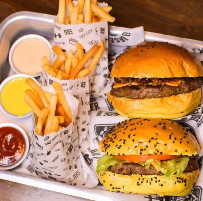 Duas batatas com hambúrguer, acompanhadas de molhos dentro de uma bandeja