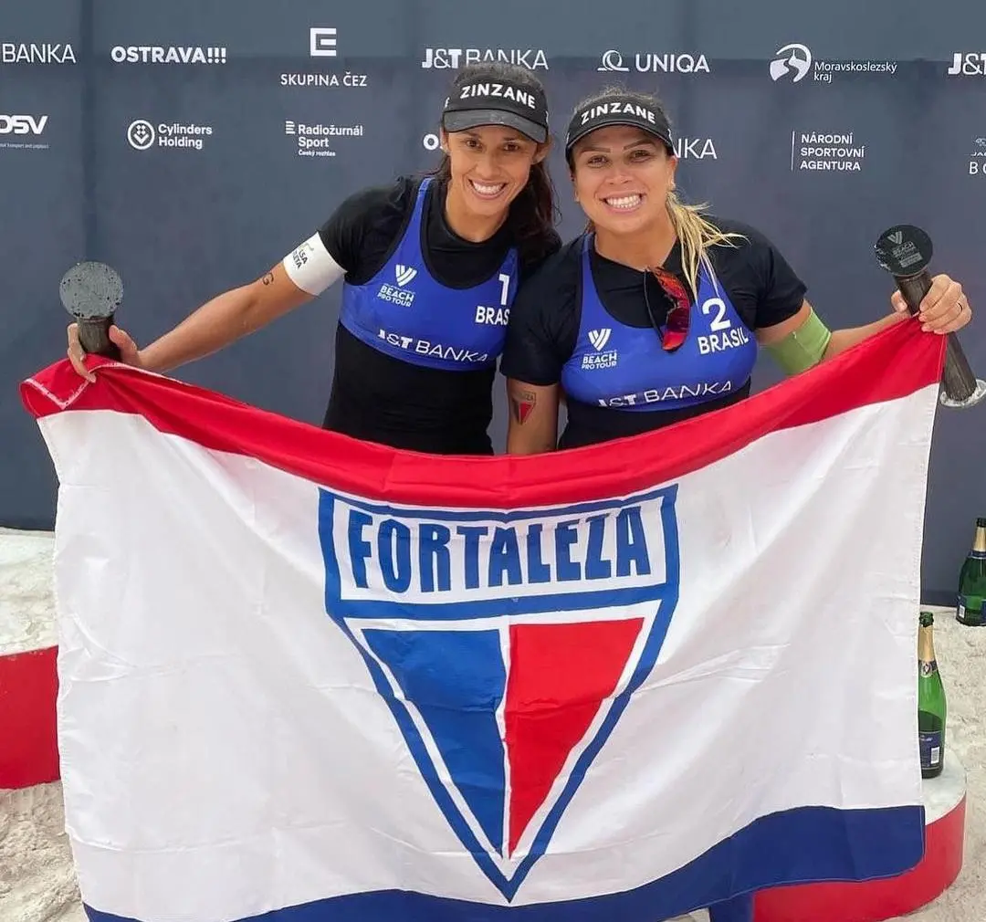 Imagem mostra duas mulheres segurando bandeira