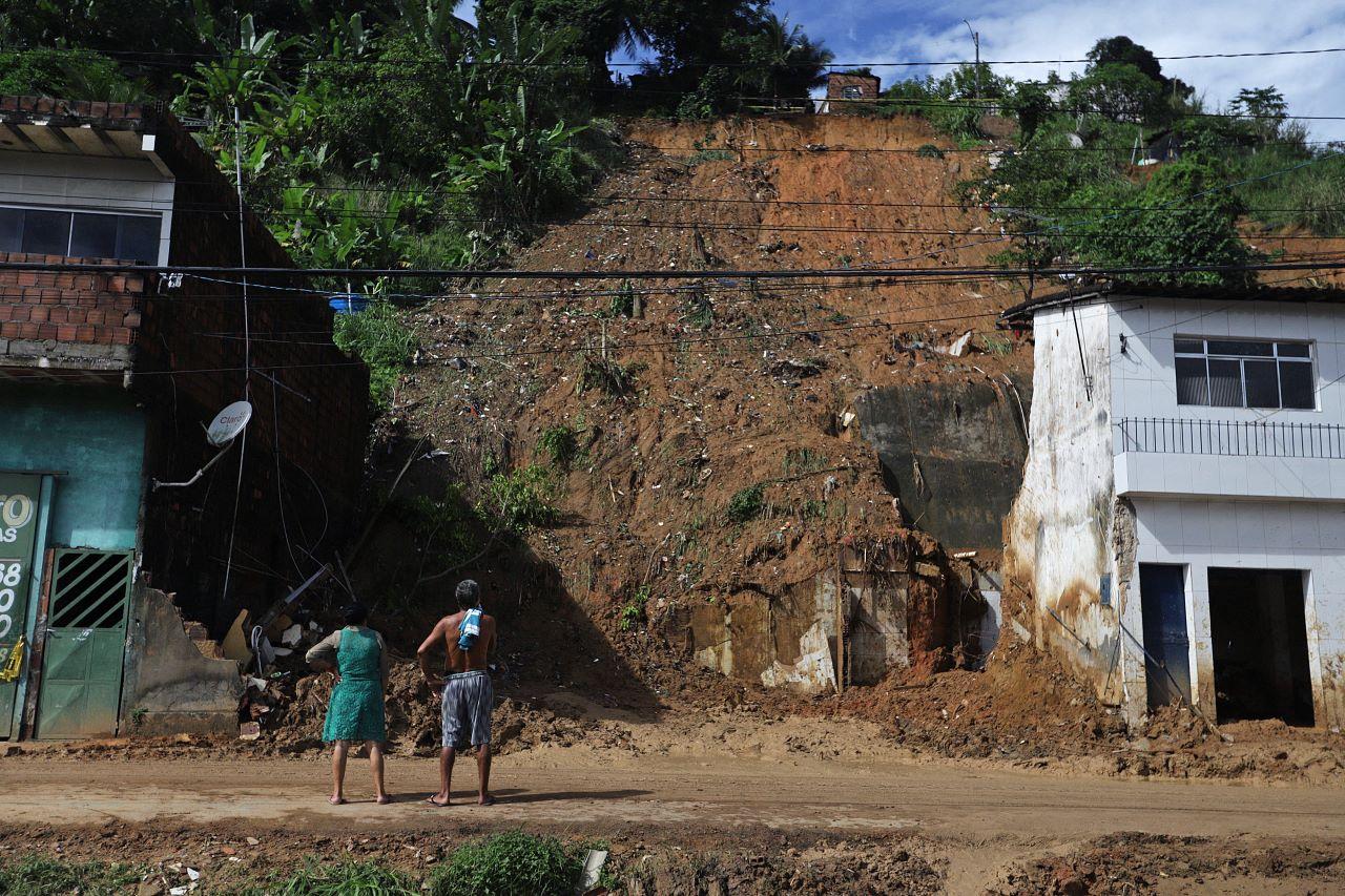 homem e mulher de costas observam encosta após deslizamento de terra em pernambuco