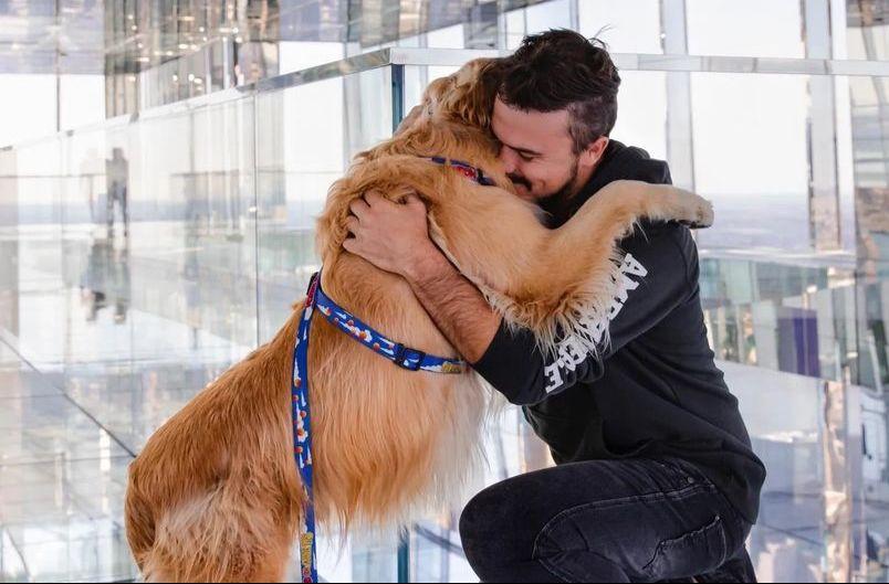 O cão Shurastey, um golden retrivier, está abraçado ao seu tutor, Jesse Koz. Ambos faleceram em uma colisão de trânsito.