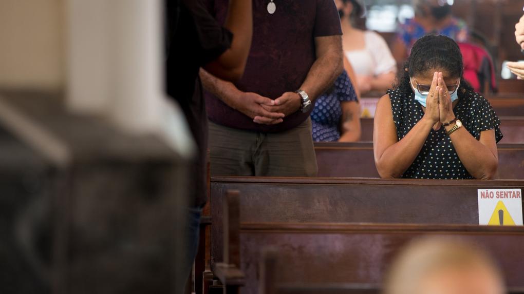 Mulher rezando em igreja de Fortaleza