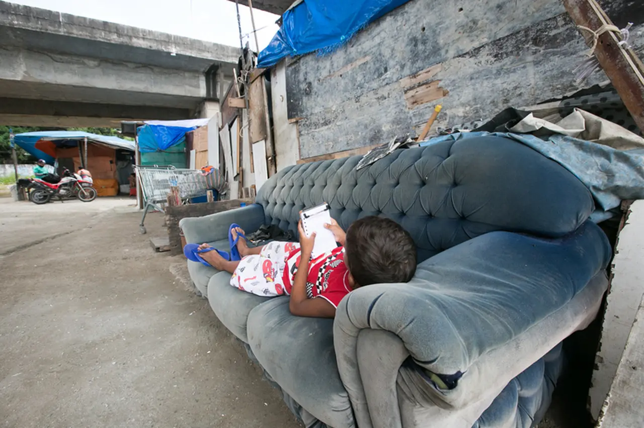 Criança lendo deitada em sofá sob viaduto