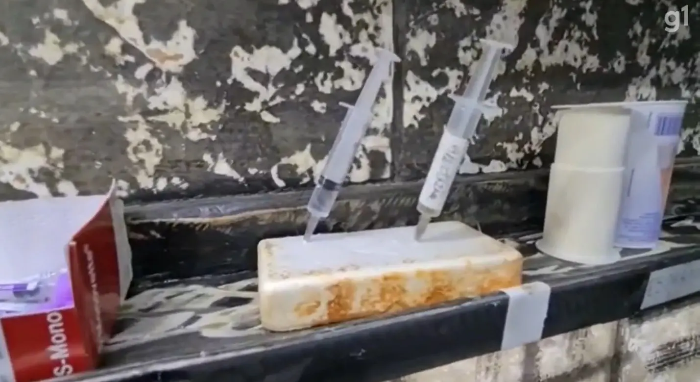 Seringas estão presas a um recipiente sujo dentro de um centro cirúrgico insalubre de uma clínica veterinária.