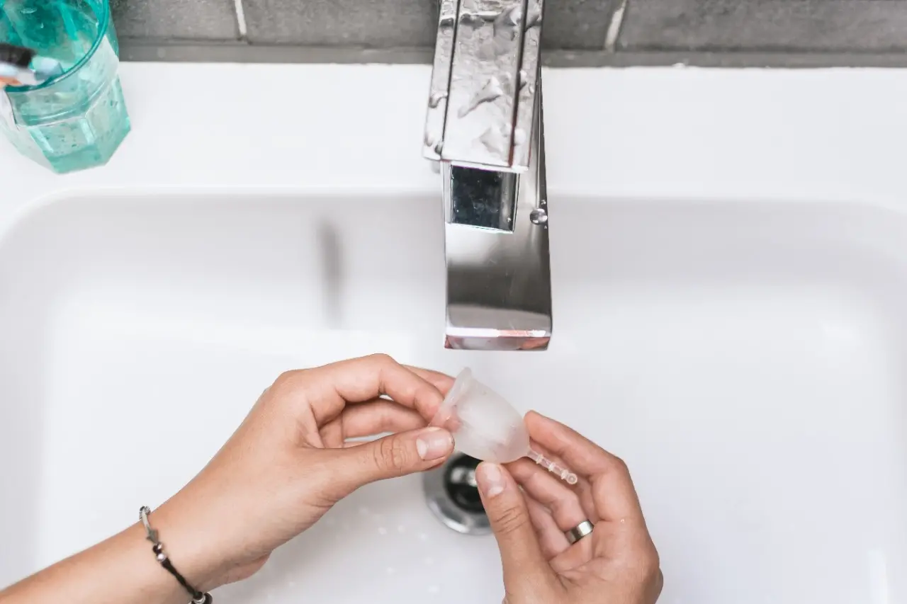 Foto de uma mulher lavando um coletor menstrual