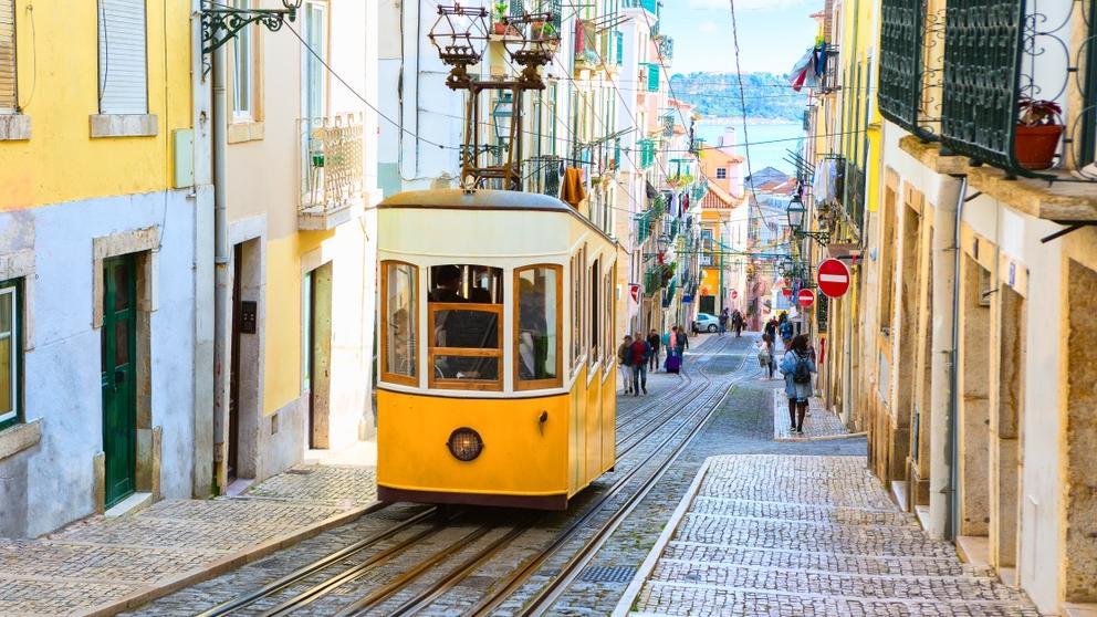Rua de Lisboa. Um bondinho amarelo passa.