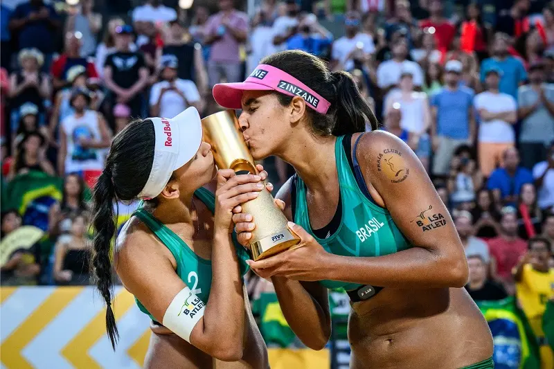 Imagem mostra duas mulheres beijando uma taça