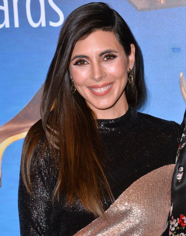 A atriz Jamie-Lynn Sigler está de frente, maquiada. Ela usa um vestido gola alta preto e dourado com lantejoulas.