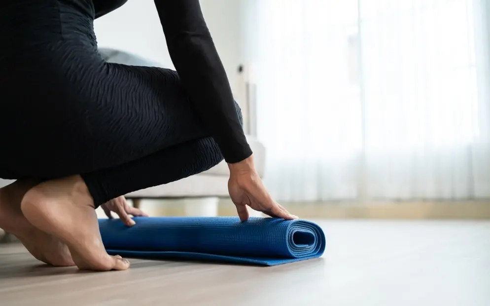 Mulher desenrola tapete de ioga.