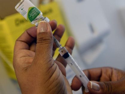 enfermeira segurando frasco de vacina contra a influenza e retirando o imunizante com uma seringa