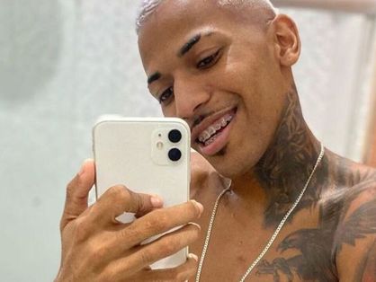 O dançarino de brega-funk Jadson Neiff tira uma selfie de frente para o espelho e mostra a língua. Ele tem tatuagens e o cabelo descolorido.
