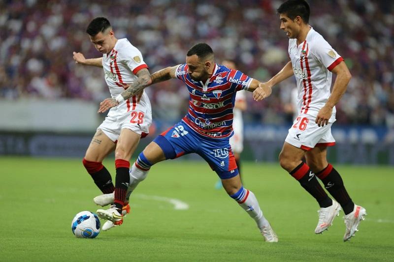 Imagem mostra jogadores disputando bola de futebol