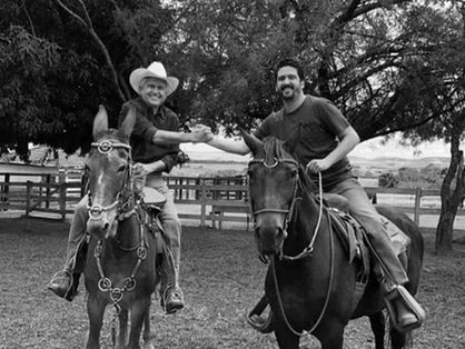 Ronaldo Caiado e Ronaldo Filho estão montados a cavalo e dão as mãos.