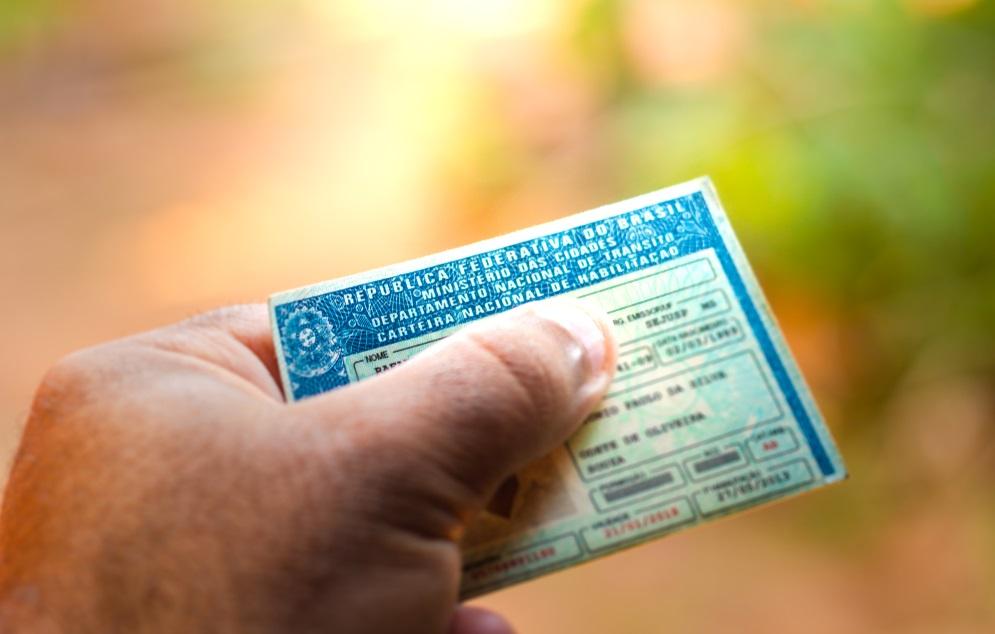 Mão segurando uma Carteira Nacional de Habilitação.