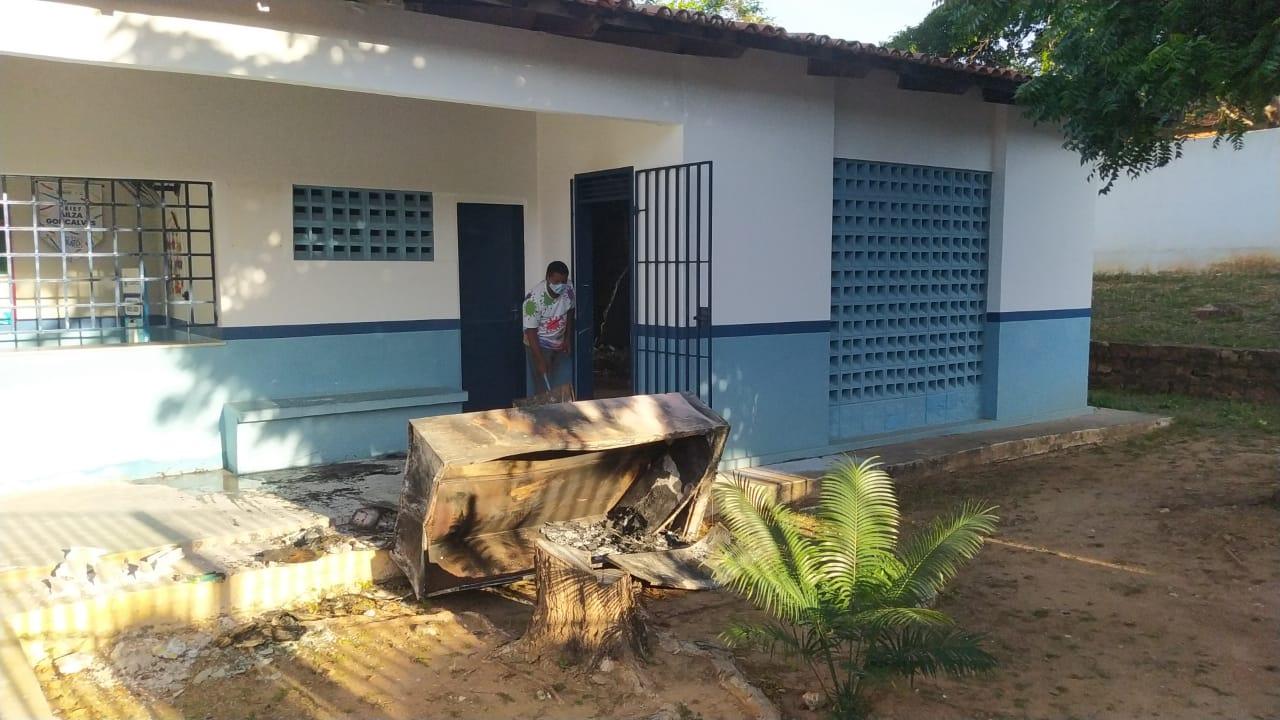 Homem retira móveis queimados de dentro de escola municipal incendiada.