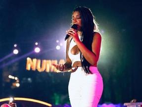 Ludmilla está vestida com uma roupa branca enquanto se apresenta no palco do projeto Numanice.