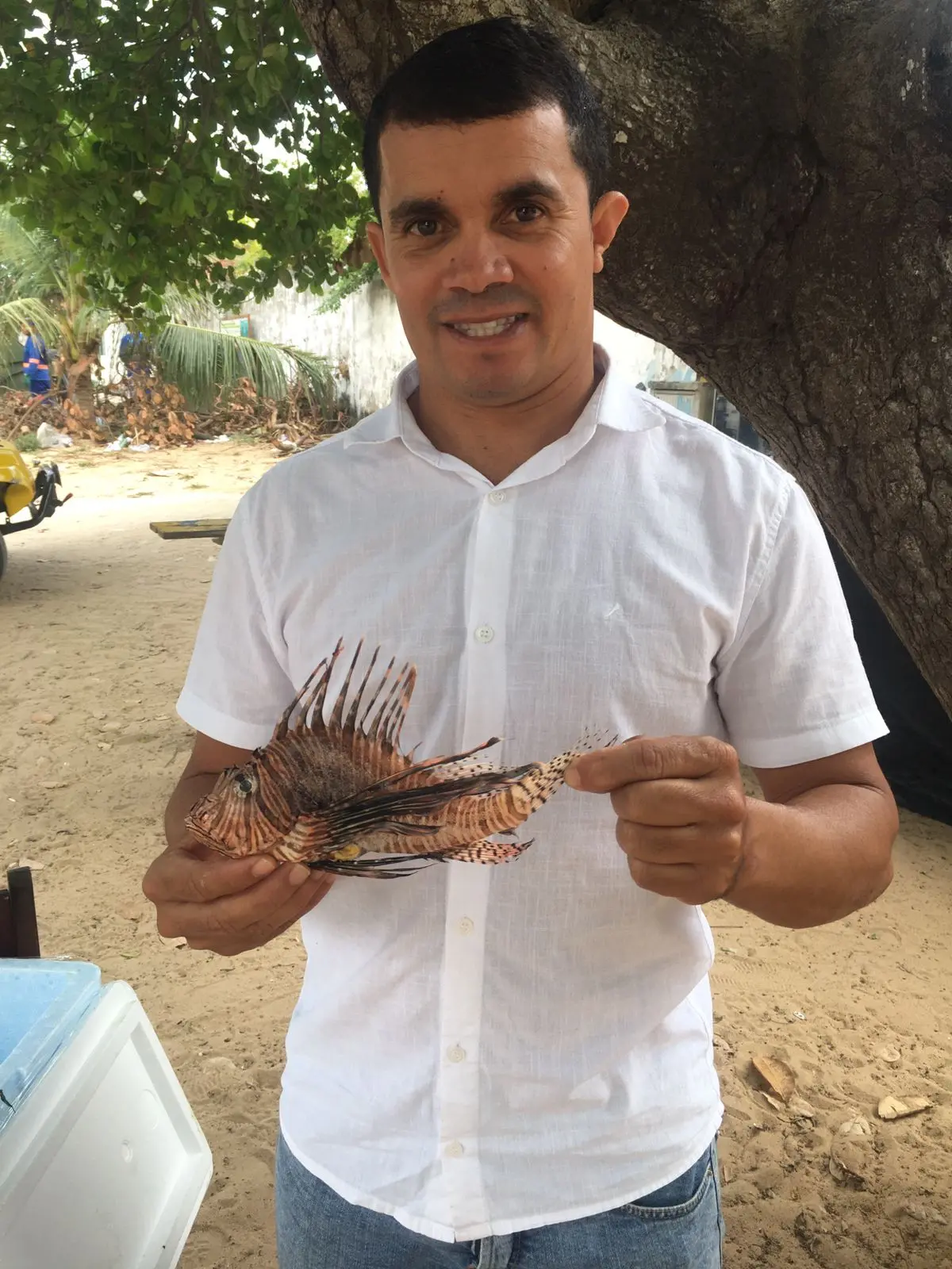 Homem segura peixe-leão