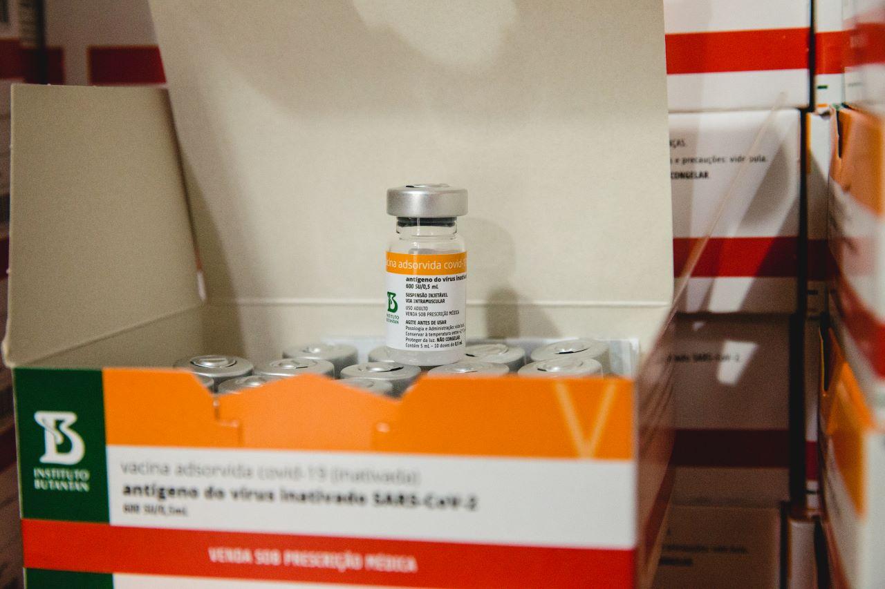 frasco da vacina coronavac em cima de caixa com vários frascos de vacina