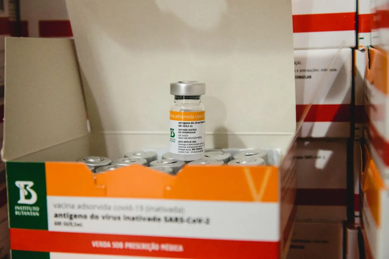 frasco da vacina coronavac em cima de caixa com vários frascos de vacina