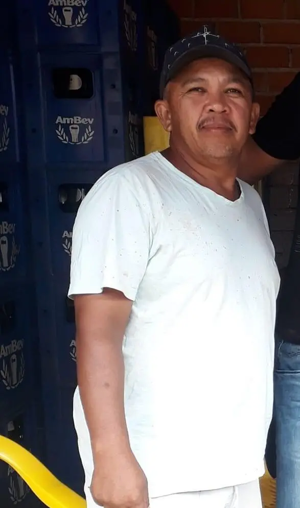 Ronaldo Pereira é um homem de meia idade. Ele está usando camisa branca e boné azul.