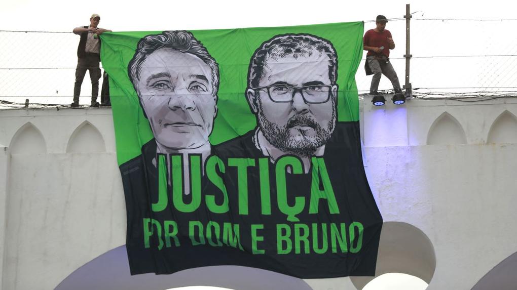 bandeira em verde e preto com imagens dos rostos de dom phillips e bruno pereira pedindo justiça pelas vítimas