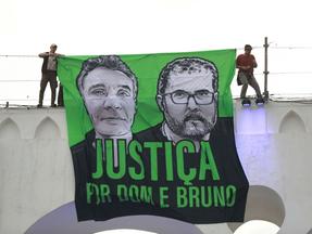 bandeira em verde e preto com imagens dos rostos de dom phillips e bruno pereira pedindo justiça pelas vítimas