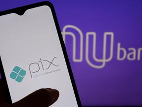 Imagem mostra um celular ligado no Pix com a logo do Nubank atrás.