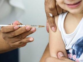 Criança recebendo dose de vacina contra a Covid-19 no braço.