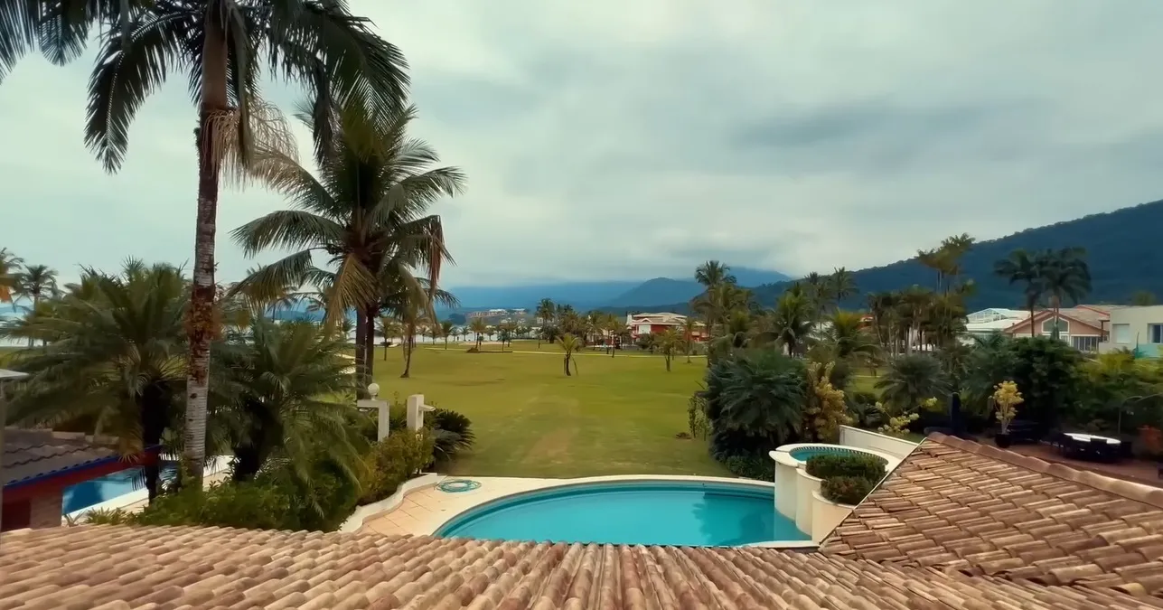A varanda da mansão é ampla e abrange um jardim e uma piscina.