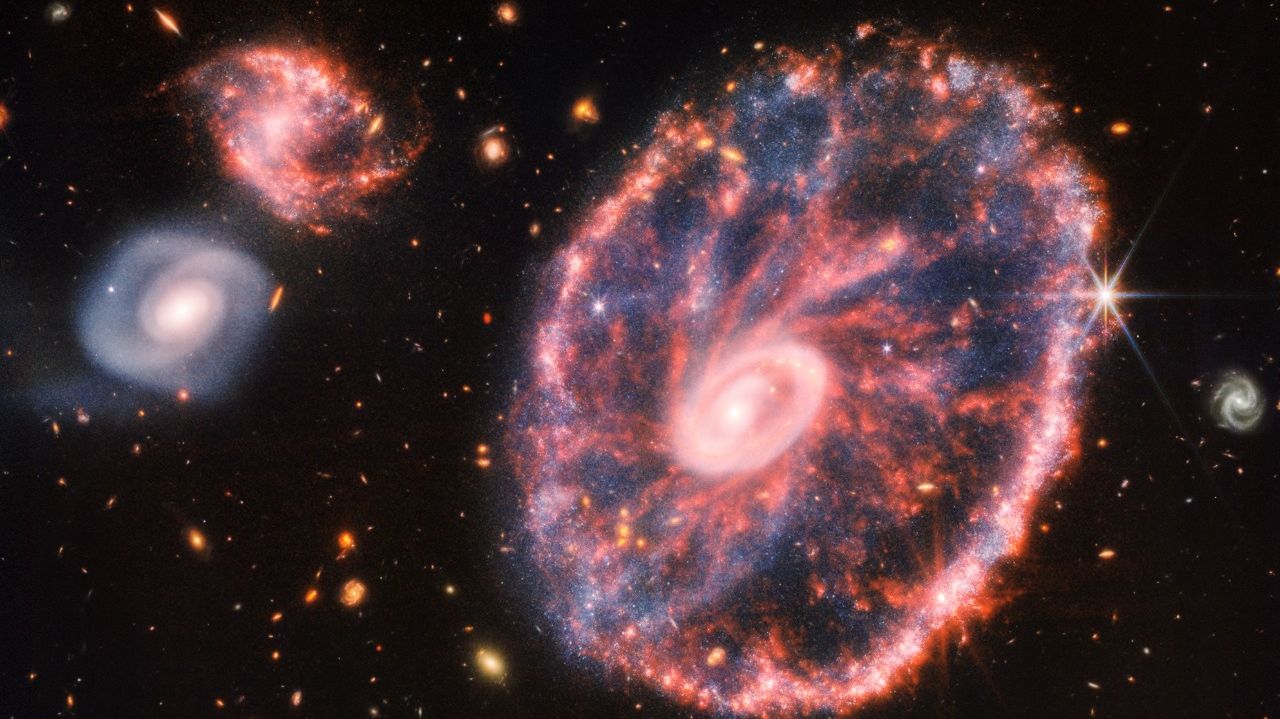 Imagem da galáxia Roda de Carro e de outras menores.