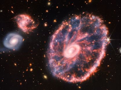 Imagem da galáxia Roda de Carro e de outras menores.