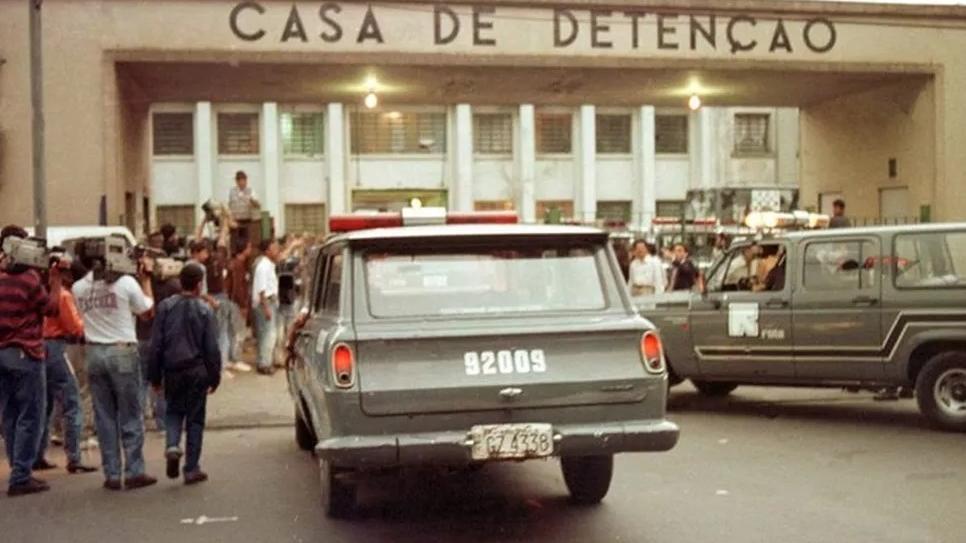 Fachada da Casa de Detenção Carandiru, em São Paulo. Carros e profissionais da imprensa aparecem na imagem.