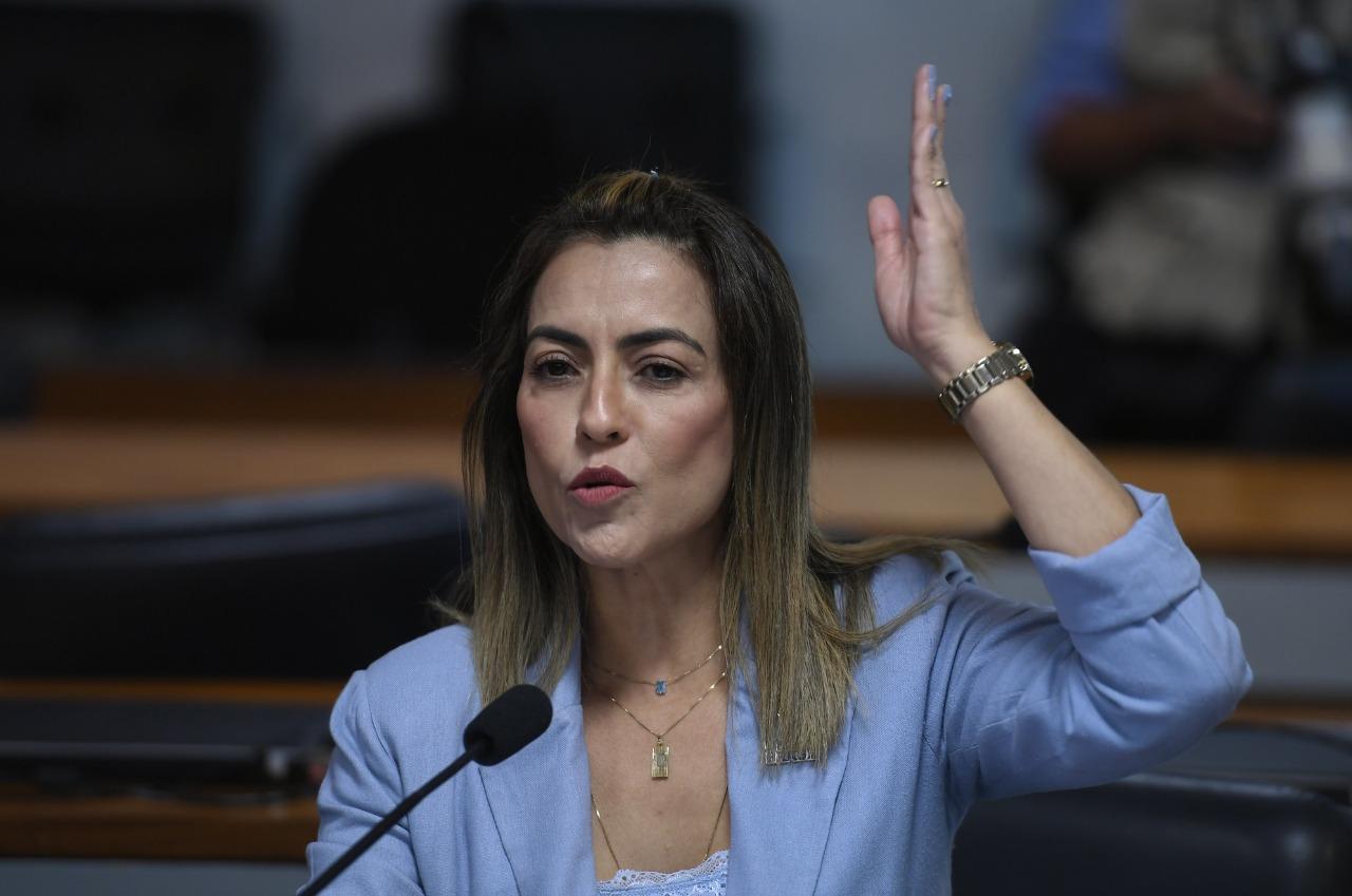 Soraya Thronicke de terno azul com a mão apontando pra cima.
