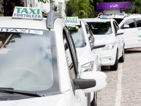 Fileira de táxis estacionados no acostamento de rua de Fortaleza