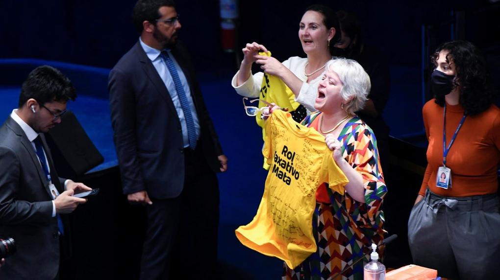 mulher balança camiseta amarela com o dizer rol taxativo mata