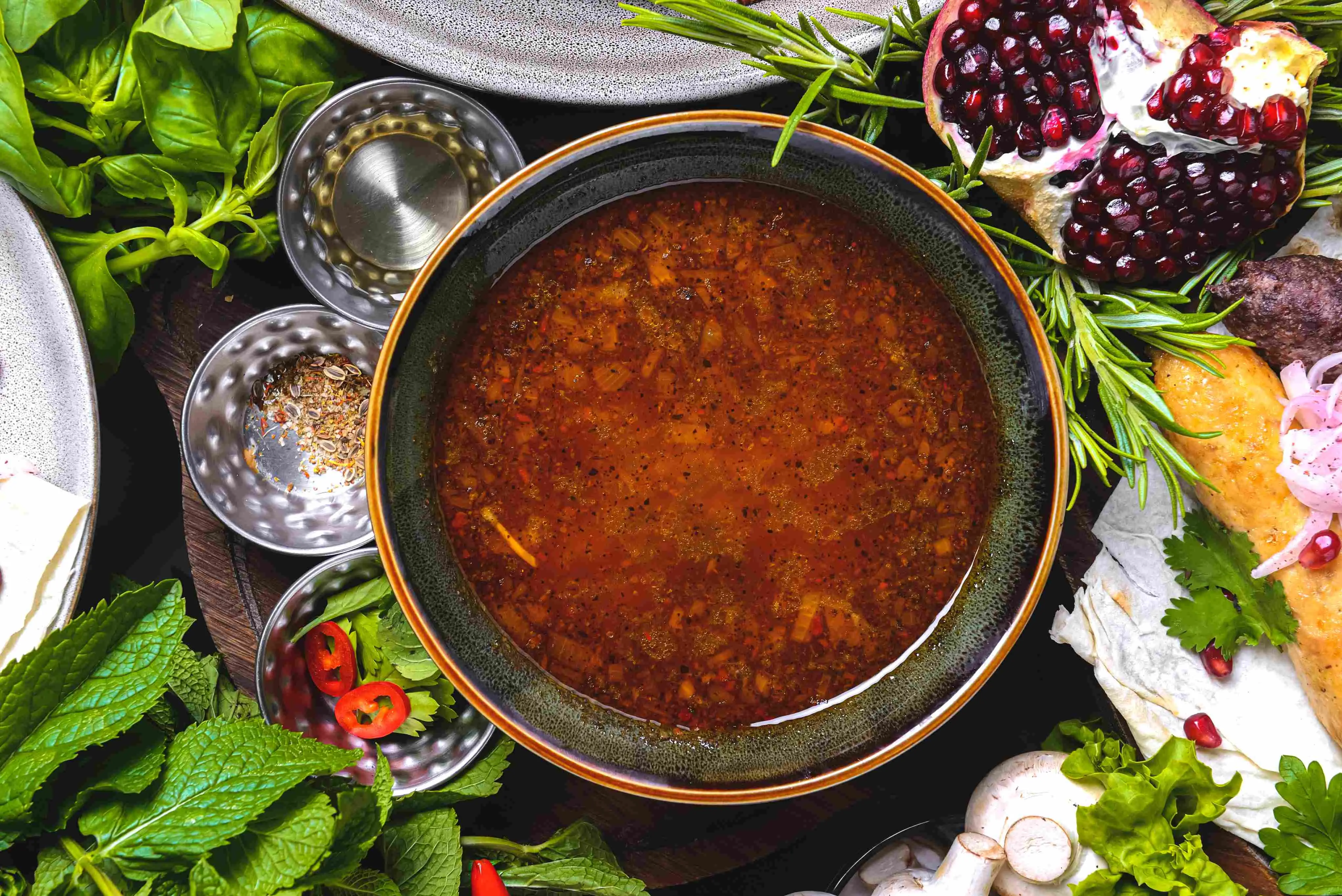 Imagem mostra recipiente com sopa de carne moída ao lado de diversas especiarias e temperos, ilustrando receitas quentes e nutritivas para serem consumidas em qualquer época do ano, incluindo o inverno