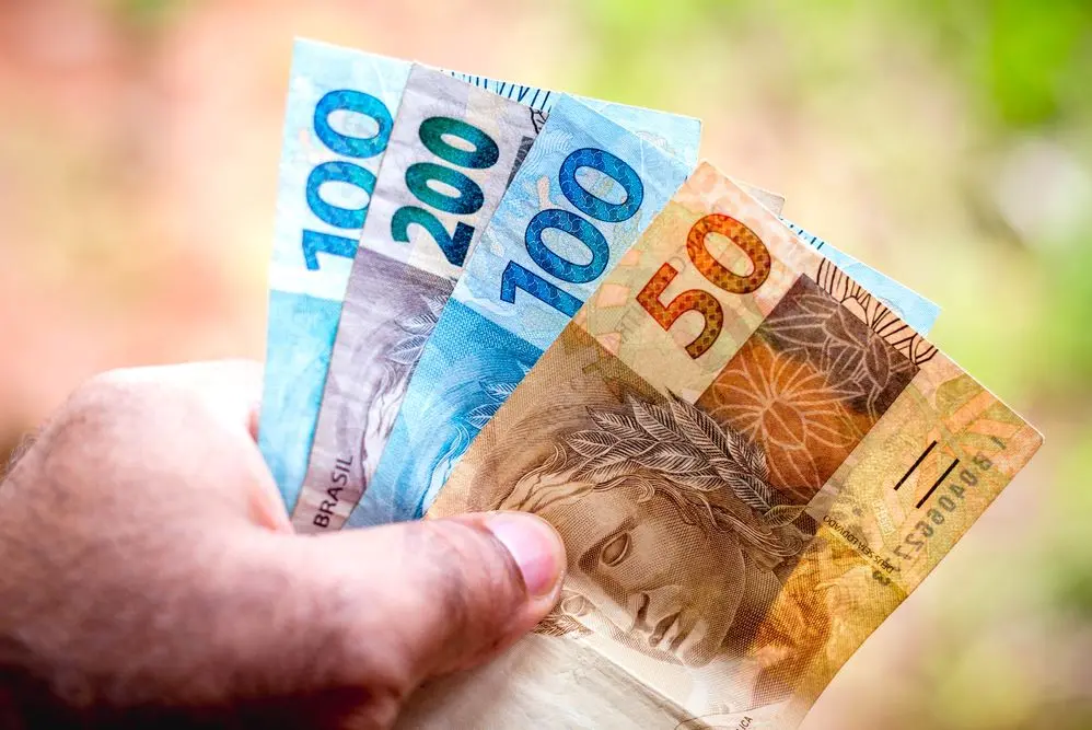 Homem segurando cédulas de dinheiro