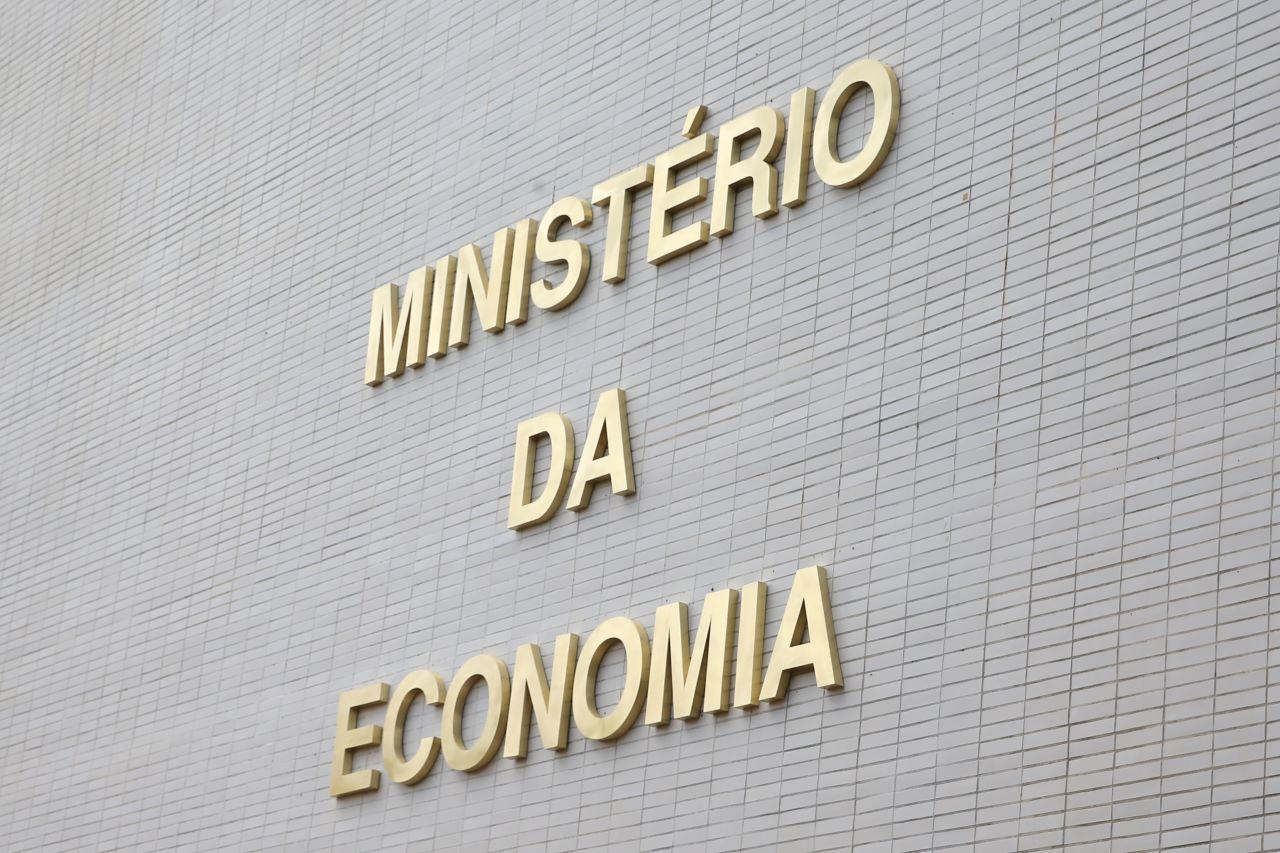 letras douradas escrevem o nome ministério da economia em fachada branca
