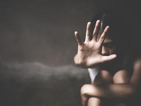 Conceito de criança vítima de estupro, menina embaçada faz gesto de 'pare' com a mão sobre fundo escuro