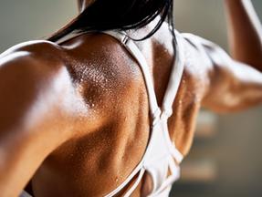 Músculos de uma mulher de costas que está flexionando os braços.