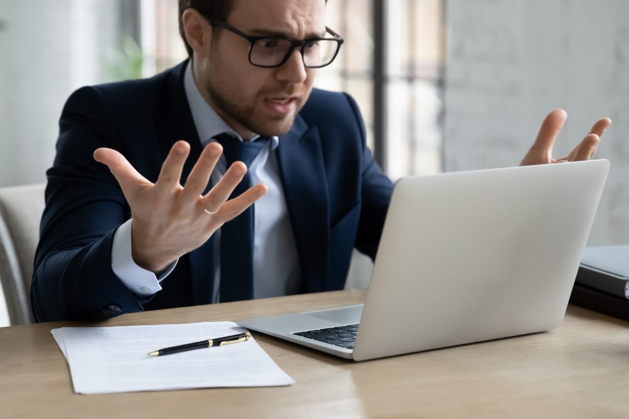 Homem de terno irritado em frente a computador