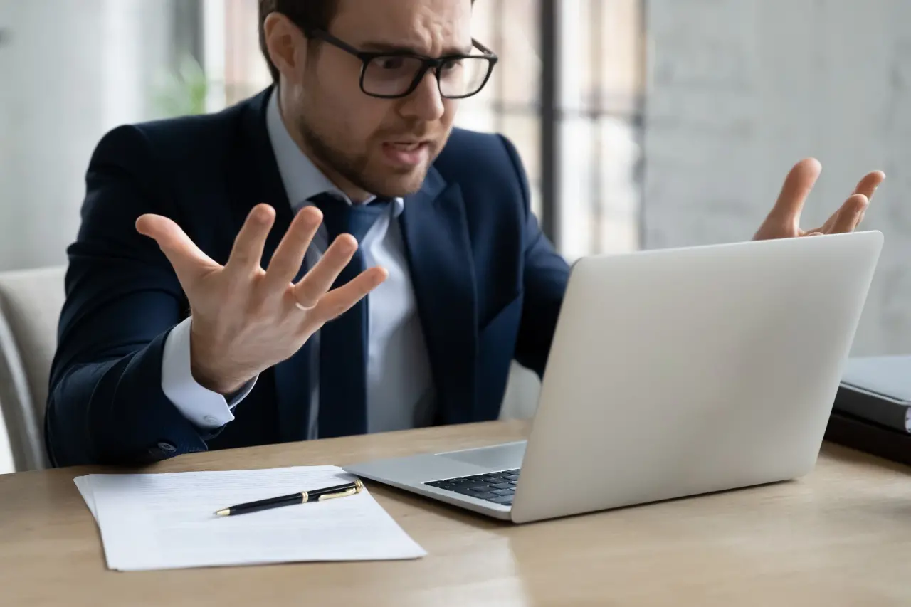 Homem de terno irritado em frente a computador