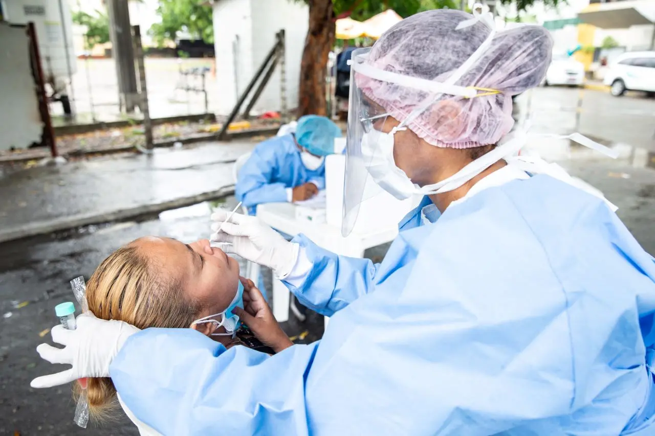 Enfermeiras aplicam teste RT-PCR em pessoa utilizando máscara contra a Covid-19.