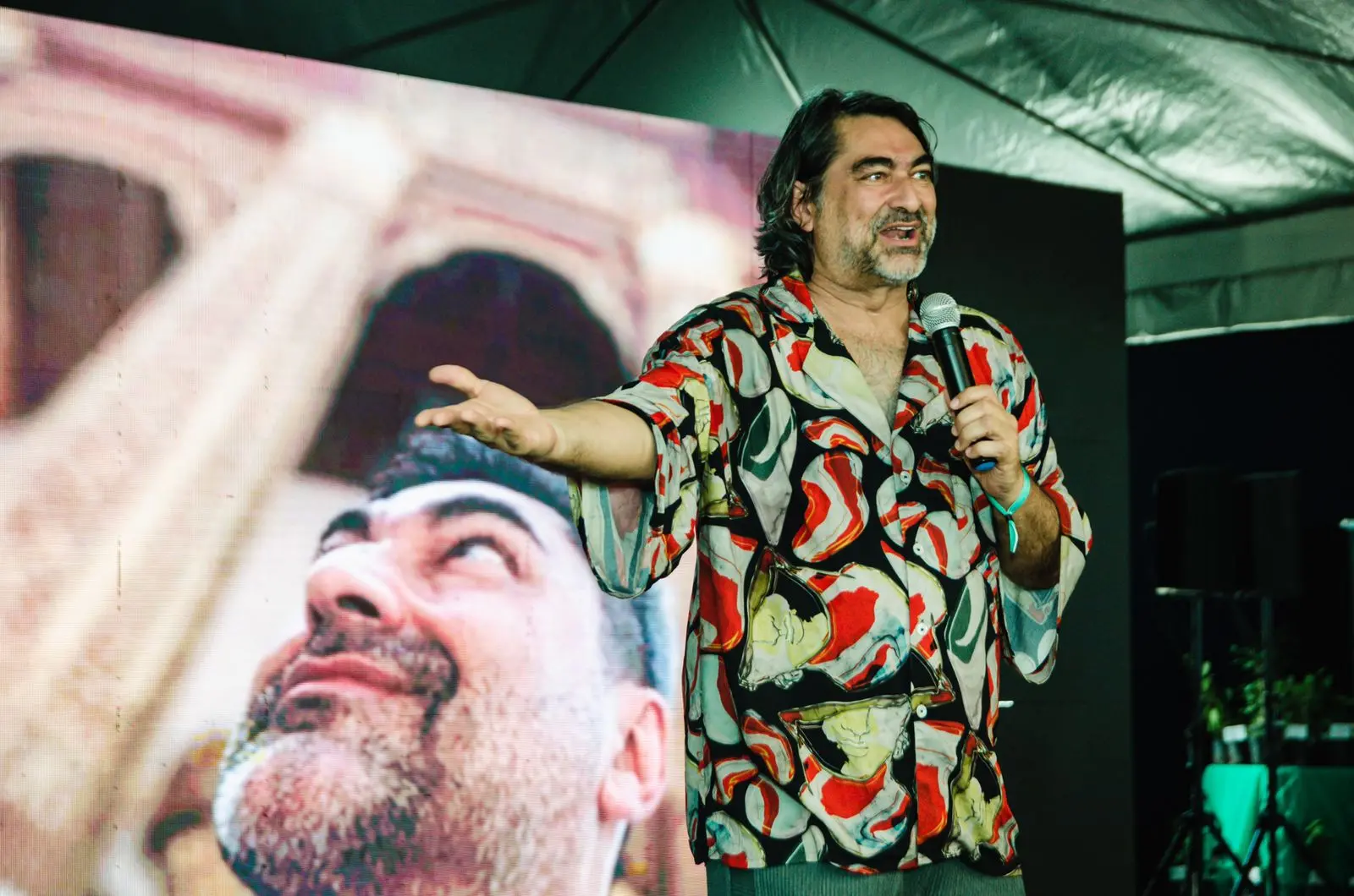 Zeca Camargo usa uma blusa estampada e fala ao microfone durante painel em evento no Cumbuco.