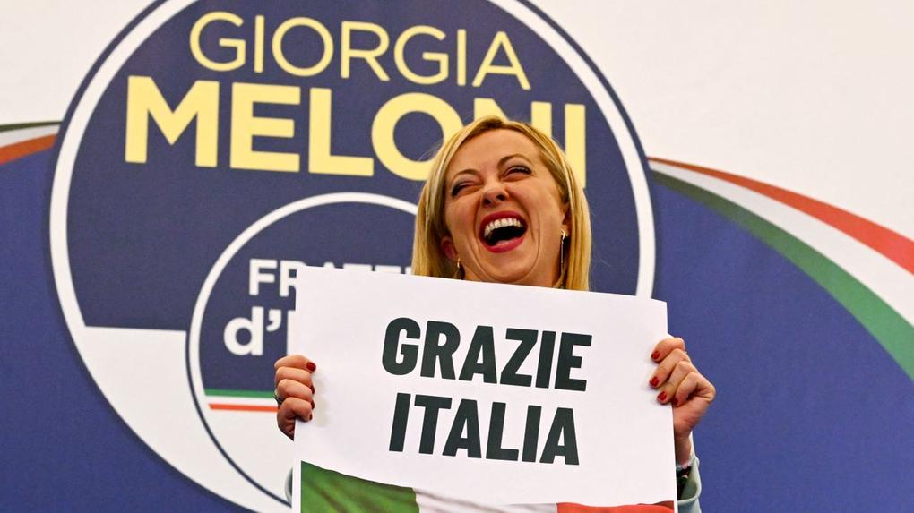 giorgia meloni segura cartaz com as palavras grazie itália