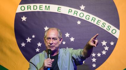 Ciro Gomes em frente à bandeira do Brasil