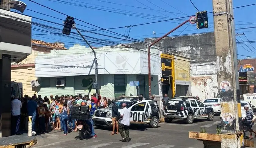 Viatura da Polícia Militar do Ceará e população aglomerada em cena de crime em Juazeiro do Norte