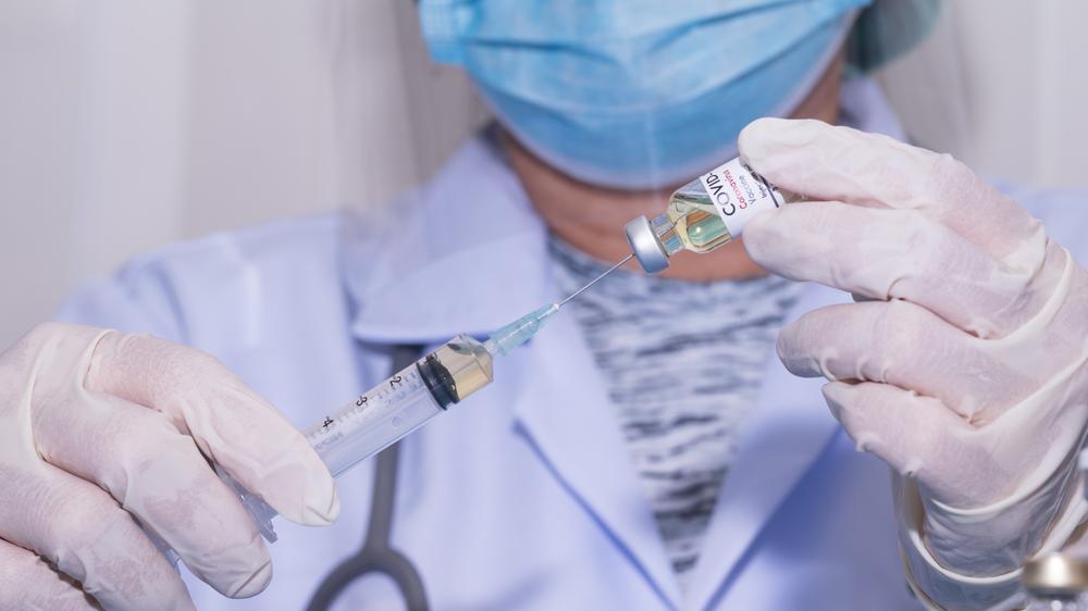 Cientista segura seringa e dose de vacina contra a Covid-19.