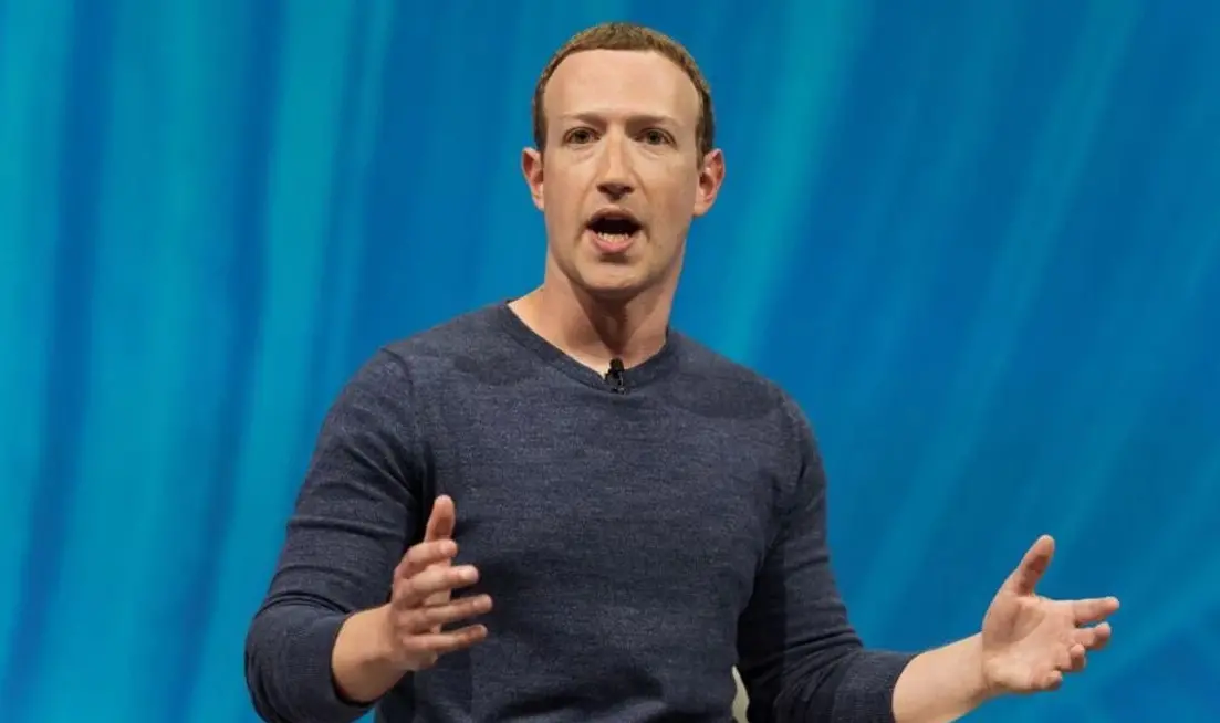 Mark Zuckerberg é um homem branco, de cabelo ralo loiro. Ele está gesticulando enquanto discursa