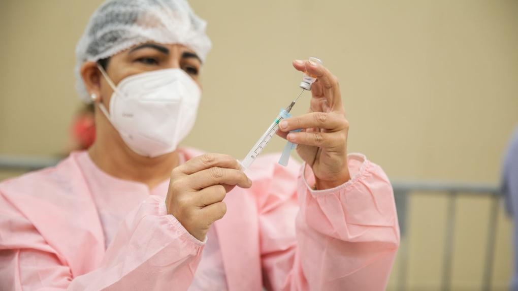 profissional da saúde injeta dose de vacina em seringa